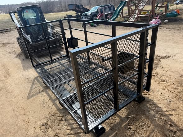 Custom built man lift basket with mesh sides mounted to a skid steer